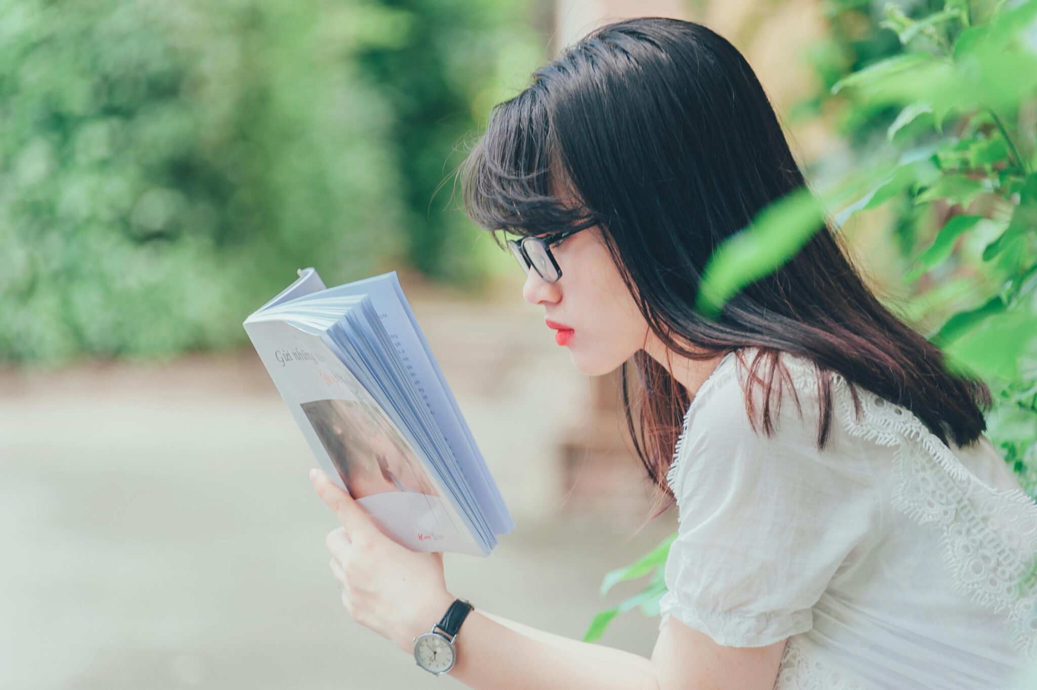 Woman Reading Book Near Bush